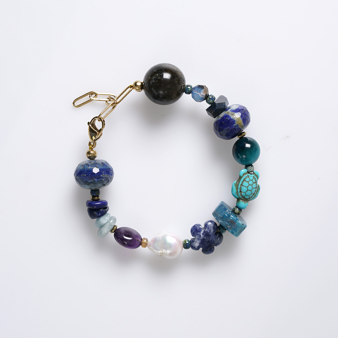 Chunky Heaven blauwe edelsteen armband met grote kralen in verschillende blauwtinten, parels en goudkleurige details.