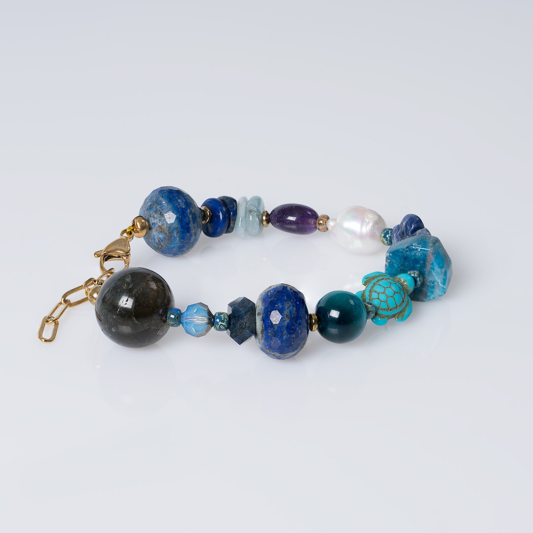 Chunky Heaven blauwe edelsteen armband met grote kralen in verschillende blauwtinten, parels en goudkleurige details.