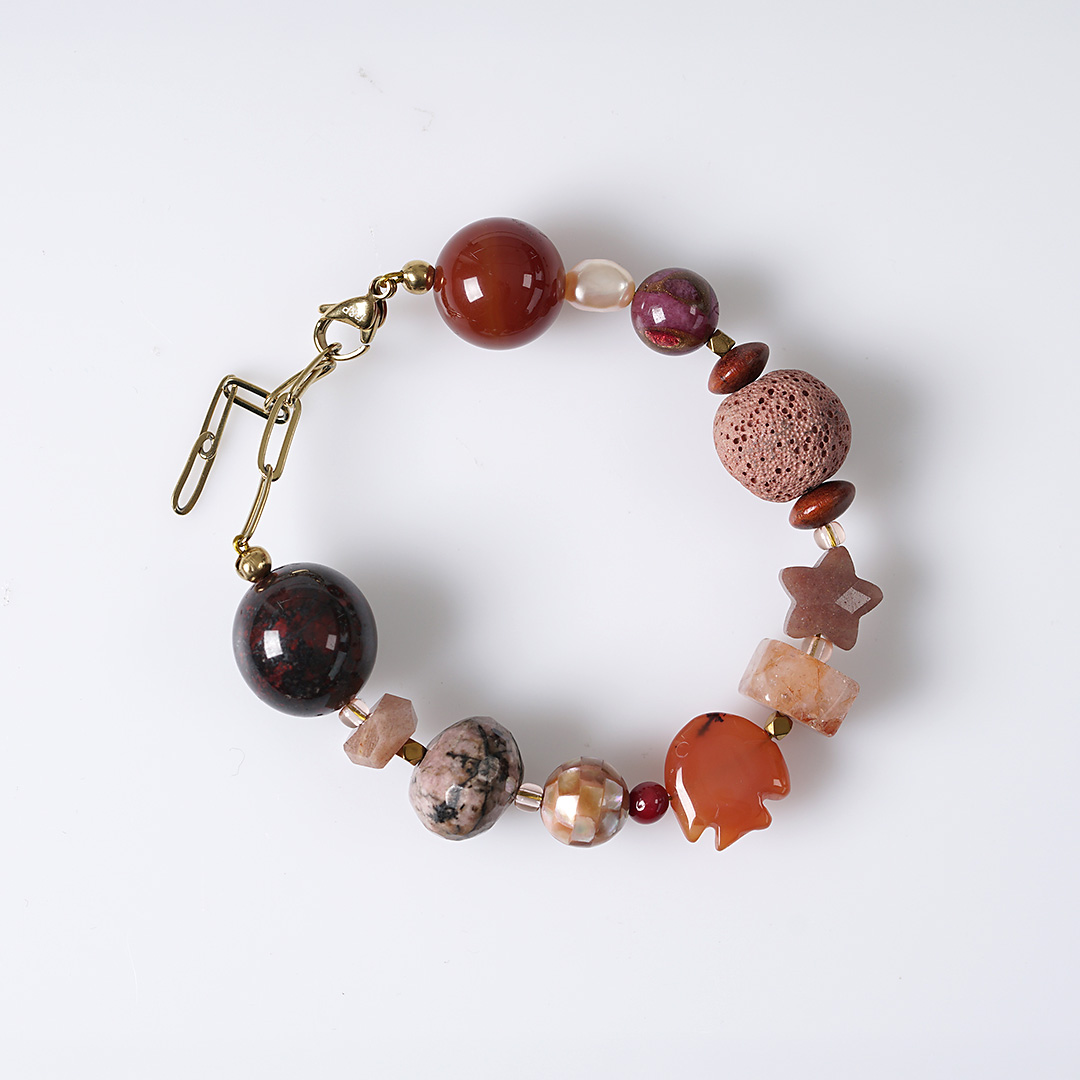 Chunky Sun oranje edelsteen armband met grote kralen in oranje en roze tinten, donkere stenen en goudkleurige details.