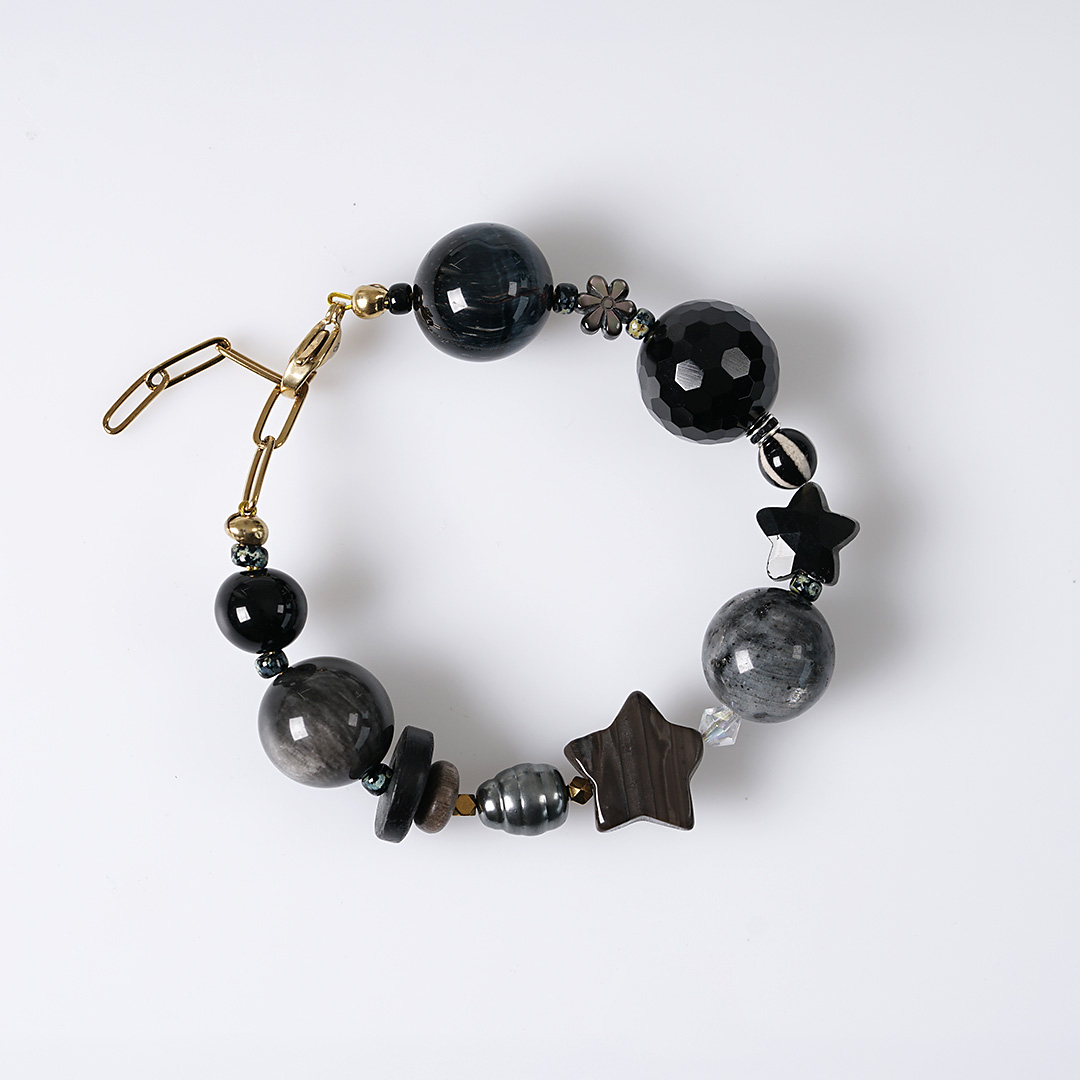 Chunky Mystery zwarte edelsteen armband met grote zwarte en grijze kralen, parels en goudkleurige details.