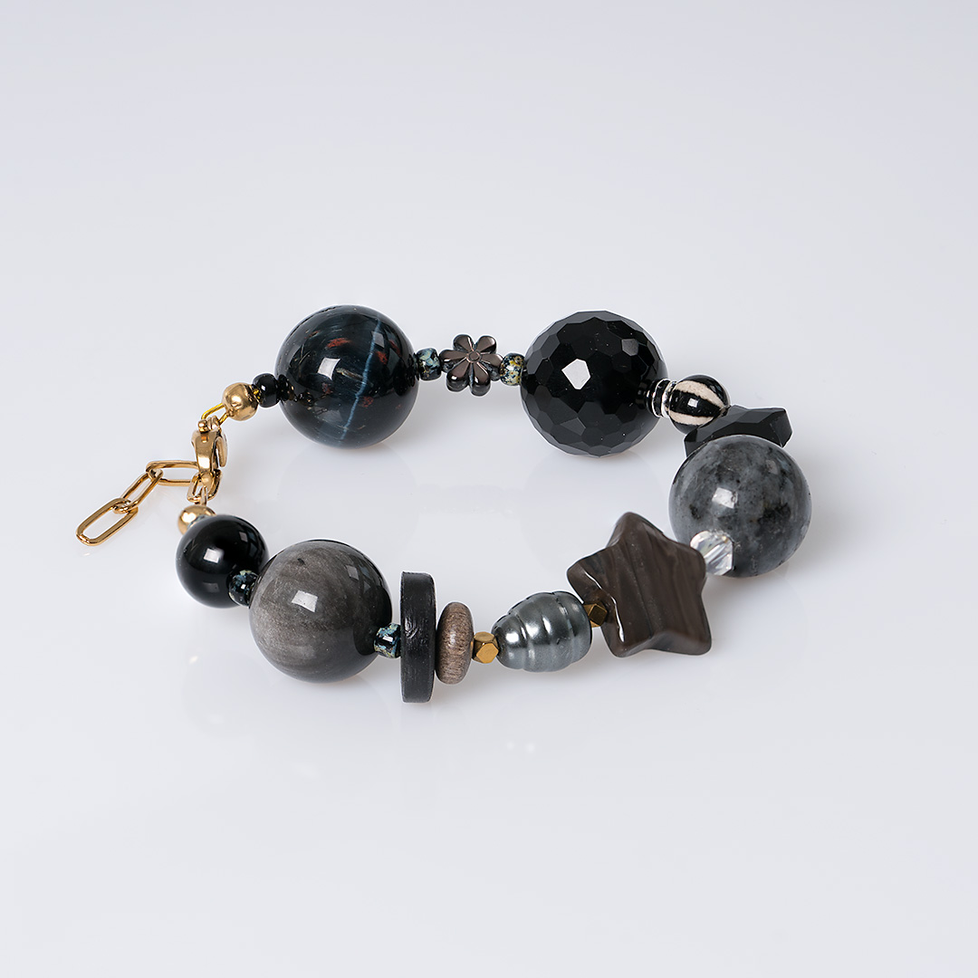 Chunky Mystery zwarte edelsteen armband met grote zwarte en grijze kralen, parels en goudkleurige details.